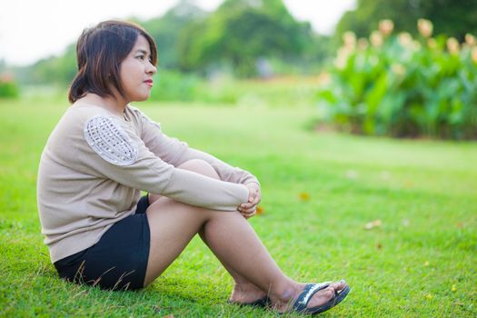 Portrait Asian woman sitting in the park. Sitting on fresh grass.