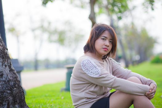 Portrait Asian woman sitting in the park. Sitting on fresh grass.
