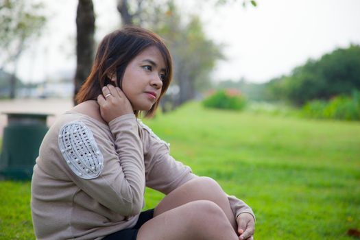 Portrait Asian woman sitting in the park. Sitting on fresh grass.