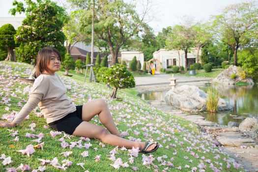 Woman sitting on lawn There are flowers on the grass in the park.
