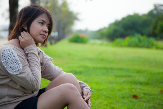 Portrait Asian woman sitting in the park. Sitting on fresh grass.