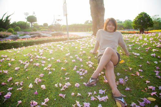 Woman sitting on lawn There are flowers on the grass in the park.