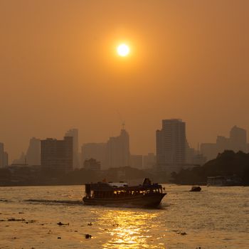 Boat traffic on the river, Bangkok City, behind a tall building in the city during the morning.