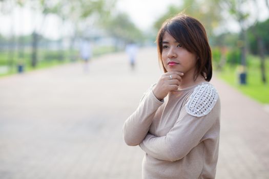 Portrait Asian woman standing in the garden and think of something.