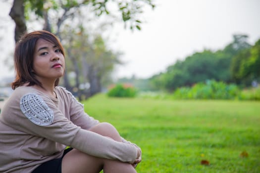 Portrait Asian woman sitting in the park. Sitting on fresh grass.