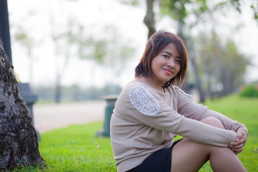 Portrait Asian woman sitting in the park. Sitting on fresh grass.