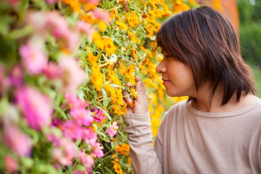 Portrait Asian woman standing near yellow flowers. And smell the flowers