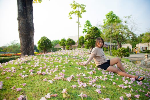 Woman sitting on lawn There are flowers on the grass in the park.