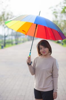 Woman holding an umbrella Standing on a walkway in the park.
