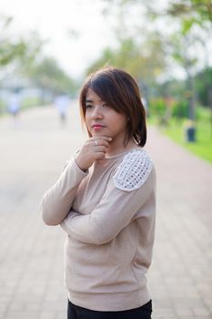 Portrait Asian woman standing in the garden and think of something.