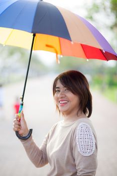 Portrait Asian woman holding an umbrella. On the path within the park.