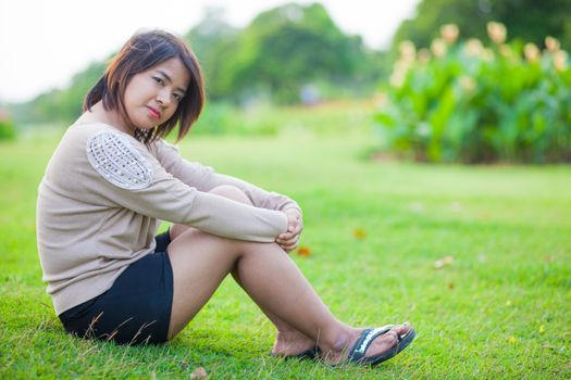 Portrait Asian woman sitting in the park. Sitting on fresh grass.