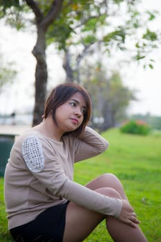 Portrait Asian woman sitting in the park. Sitting on fresh grass.