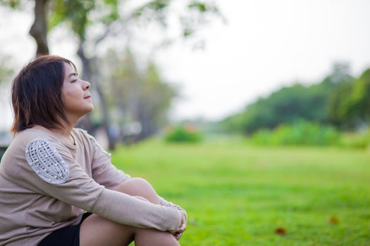 Portrait Asian woman sitting in the park. Sitting on fresh grass.