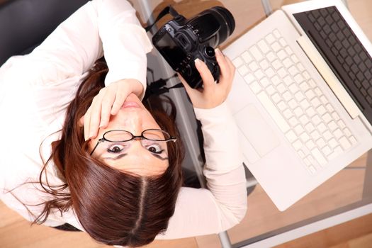 A young adult woman reviewing and downloading photos from a digital camera.