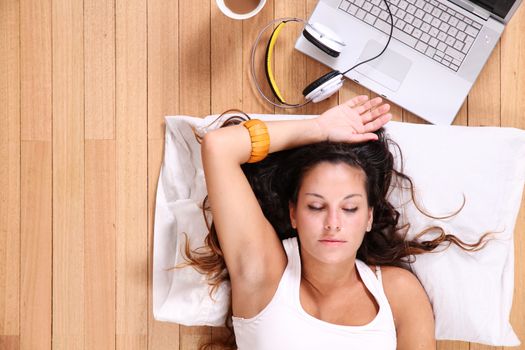 A girl laying on the Floor after surfing on the Internet with a Laptop.