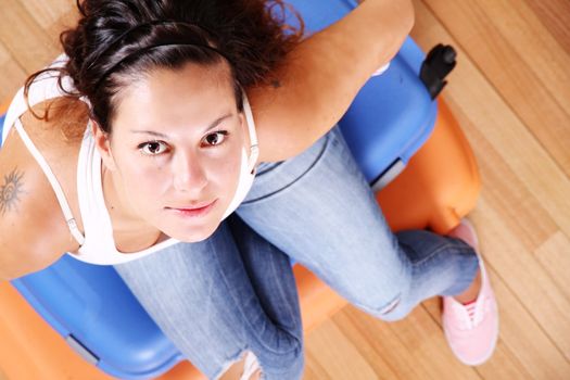 A young woman sitting on a stack of suitcases.