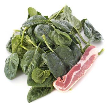 raw spinach and bacon in front of white background