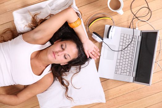 A girl laying on the Floor after surfing on the Internet with a Laptop.