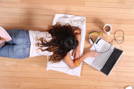 A girl laying on the Floor while surfing on the Internet with a Laptop.