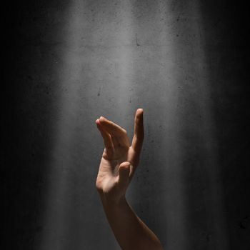 woman's hand reaches for the light rays, conceptual image of striving for freedom