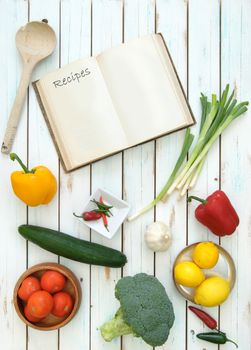 Open blank recipe book surrounded by fresh ingredients 