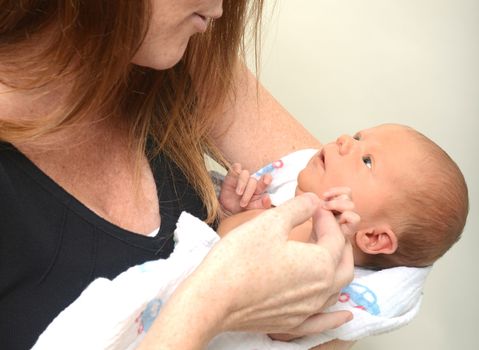 Alert newborn looking up at mother in amazement