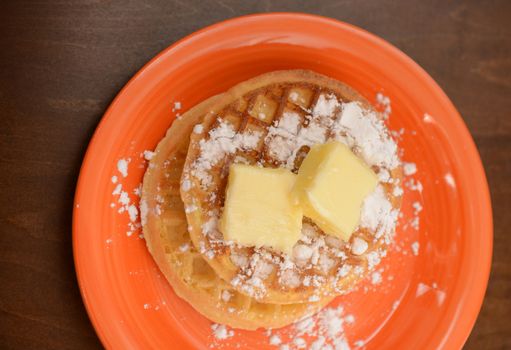 two classic waffles with powdered sugar and butter