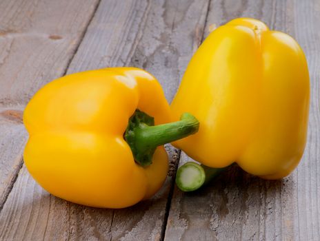 Two Ripe Yellow Bell Peppers isolated on Rustic Wooden background