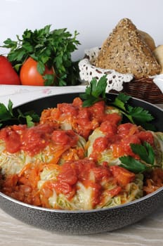 stuffed savoy cabbage in a pan under the onion and carrot gravy