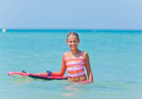 Summer vacation - Happy cute girl having fun with surfboard in the ocean