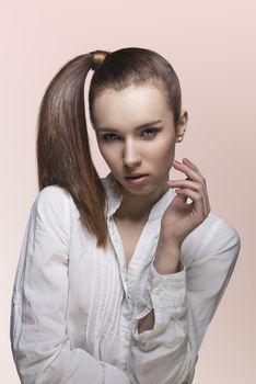sensual young lady with brown hair, white shirt and brown smooth ponytail looking in camera