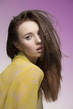 sensual female with sexy yellow transparent nightgown looking in camera and posing with her long brown dishevelled hair-style
