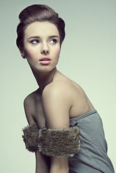 very sexy and pretty young girl in gray with arm fur and hairstyle, looking on left. Color in fashion