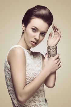 portrait of sexy brunette girl in fashion pose with creative hair-style, cute make-up and big bracelet