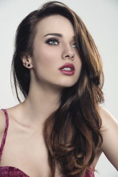 close-up portrait of sensual brunette woman with long smooth hair, make-up and splendid eyes, wearing red lingerie