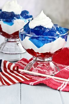 Gelatin layered dessert of cubes of red and blue jello with white flufy whipped cream for the Fourth of July holiday. Shallow depth of field.