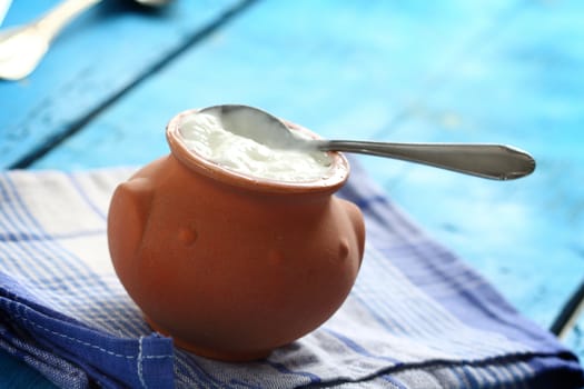 Homemade yogurt in a ceramic pot and spoon