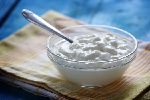 Homemade yogurt in a glass bowl and spoon