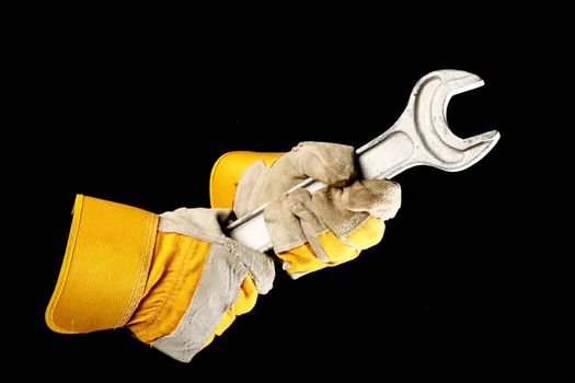 leather work gloves holding a  wrench over black 