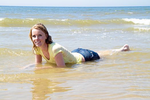 Beautiful blonde woman relaxing in the water from the north sea in the Netherlands