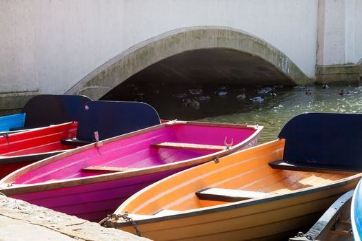 Colourful rowing boats, moored near a bridge