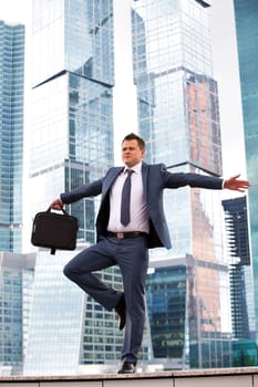 successful businessman opened his arms to the sides of office buildings in the background