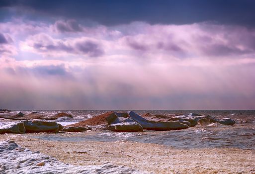 Shore line of Lake Ontario in the winter season. There is a purple glow to the sky. 