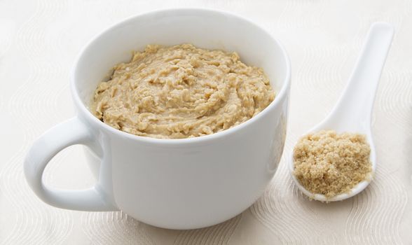 cup filled with oatmal,with a spoon of brown sugar