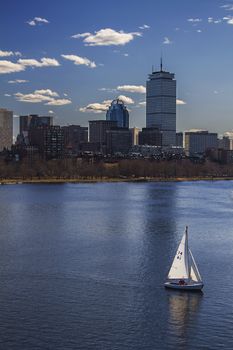 small sail boat in Boston harbor with downtown as a background