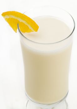 Vanilla milkshake with a slice of orange on the side against a white background