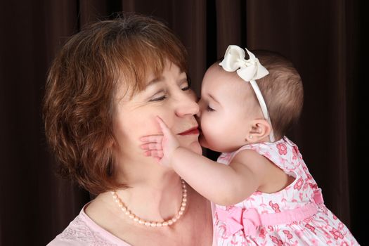 Baby granddaughter giving grandmother a kiss on the cheek