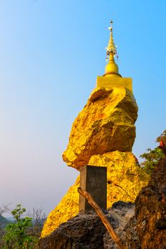 golden pagoda on  golden rock stone on mountain with blue sky in background