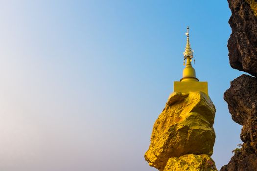 golden pagoda on golden rock stone on mountain with blue sky in background
